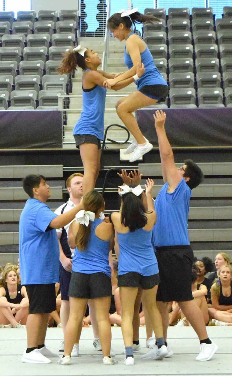 Westside Eagle Observer/MIKE ECKELS Izthel Martinez (upper right) is thrust high into the air by teammate Desi Meek (upper left) and other members of the Decatur High School cheer team during the teams' UCA Cheer Camp competition at Fayetteville High School June 23.
