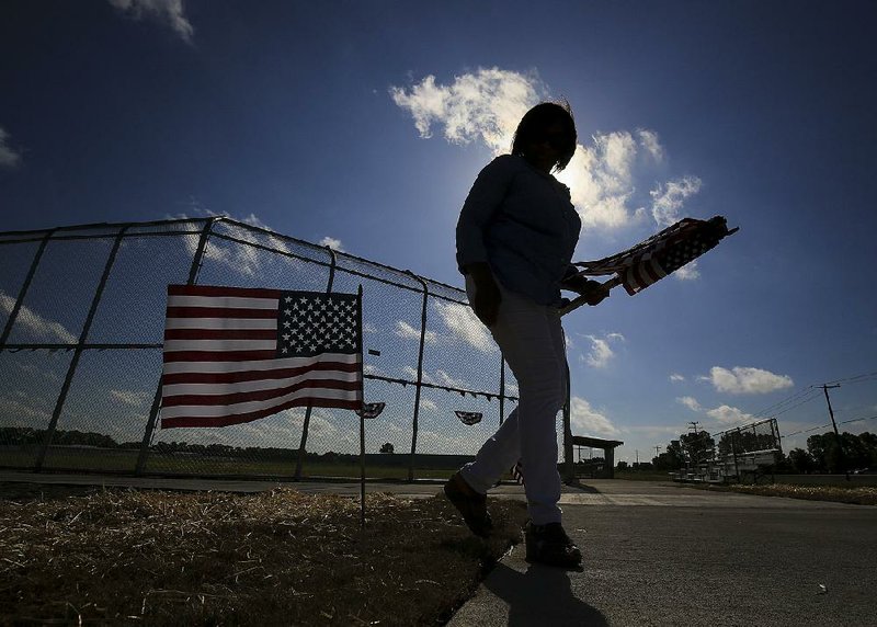 Tamara Kelley puts out flags at the new College Station Community Sports Complex on Wednesday. A 1997 tornado destroyed the previous ball field in the Pulaski County community.  