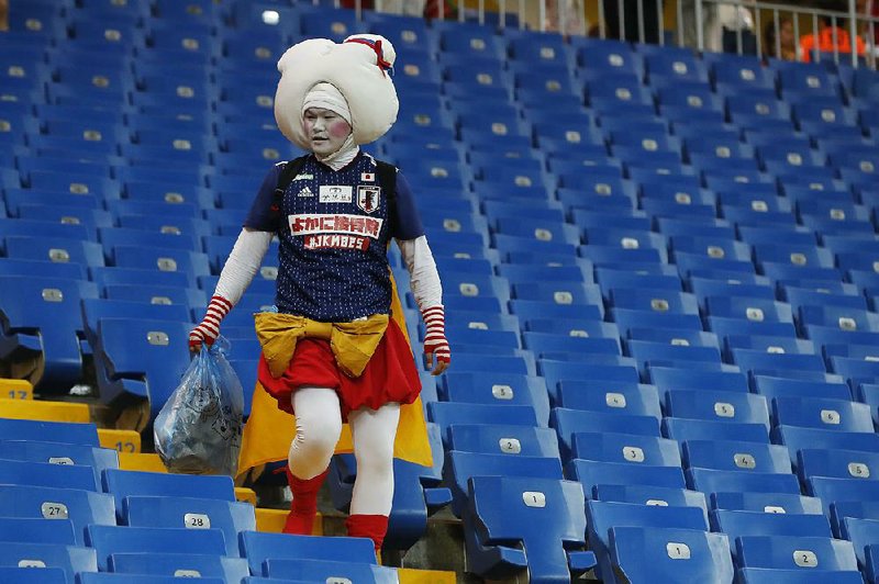 A soccer fan of Japan collects trash in the stands Monday after the country’s round of 16 World Cup loss to Belgium. Japanese players even left their dressing room at Rostov Arena spotless.  