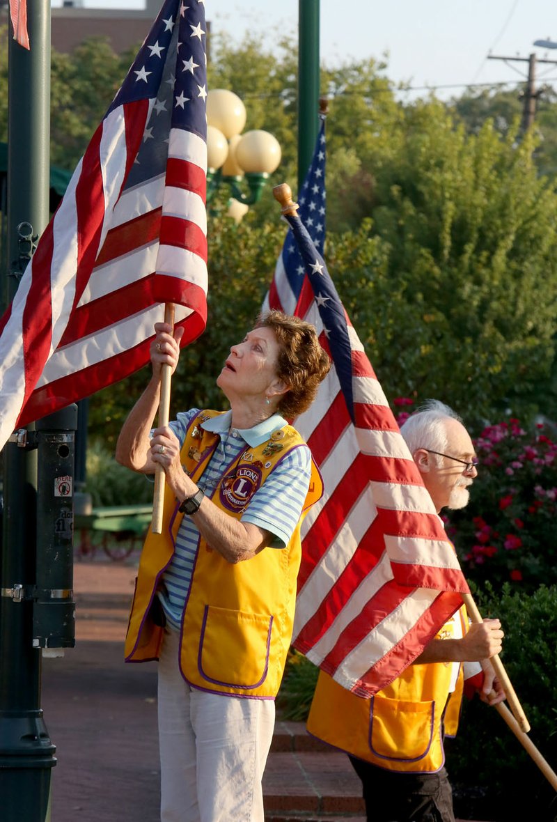 NWA Democrat-Gazette/DAVID GOTTSCHALK Ruth Cohoon (left) and Stuart Jones, both Fayetteville Lions Club members, post U.S. flags on Dickson Street in Fayetteville. Cohoon, the first women's athletic director at the University of Arkansas, was also became the first female memeber of the Fayetteville Lions Club in 1987.