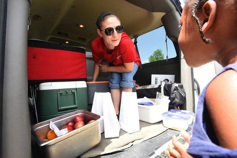 NWA Democrat-Gazette/FLIP PUTTHOFF Katrina Cross hands out lunches to children Tuesday for First United Methodist Church of Bentonville. The church delivers free lunches to youngsters at four sites in the Bentonville School District in a program started this summer.