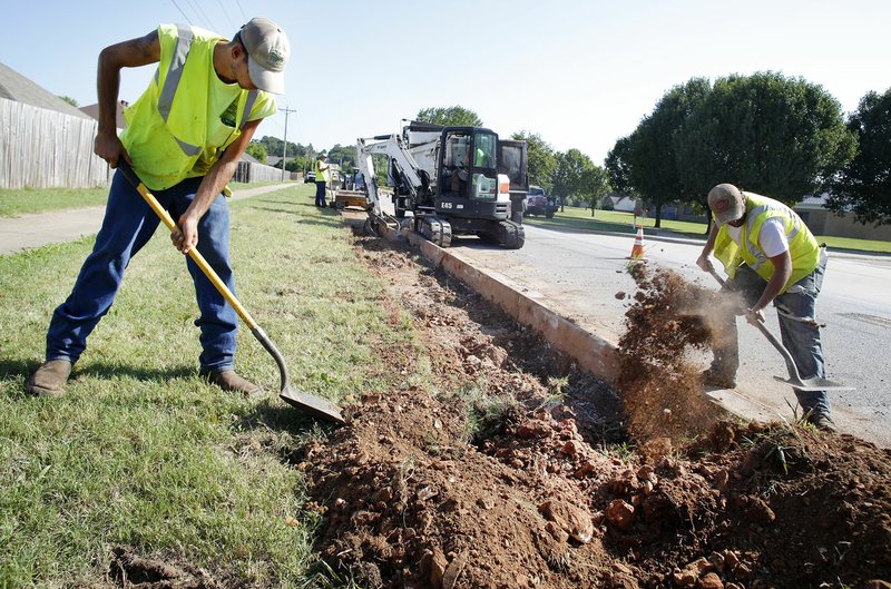 NWA Democrat-Gazette/DAVID GOTTSCHALK Donavon Taffner (left) and Levi Van Zant, both with Fayetteville's Transportation Division, clear dirt June 28 during work on Salem Road in Fayetteville. A project to widen and stripe Salem and Crystal Drive is intended to improve traffic and make the area near Holcomb Elementary School safer. The city has allotted about $50,000 out of its transportation bond fund to make pedestrian safety improvements at Butterfield, Holcomb, Washington and Owl Creek schools.