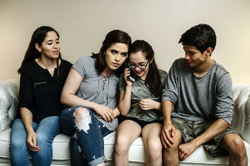 Yadira Lopez looks on as her children Juana Barrios, Andrea Barrios and Oscar Barrios speak by phone with their father, who was detained in Iowa by immigration authorities in May. 