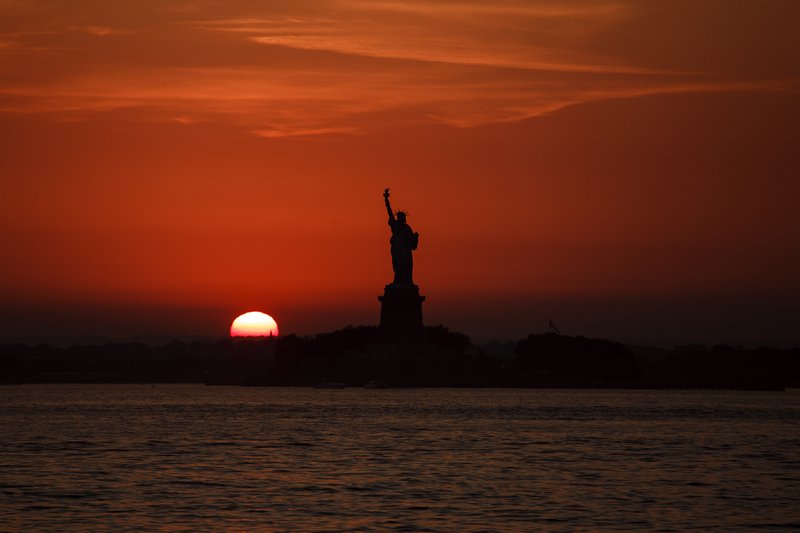 FILE - In this July 1, 2018, file photo, the sun sets behind the Statue of Liberty in New York. Record high temperatures have been recorded over the past week in the U.S. and elsewhere. (APPhoto/Andres Kudacki, File)