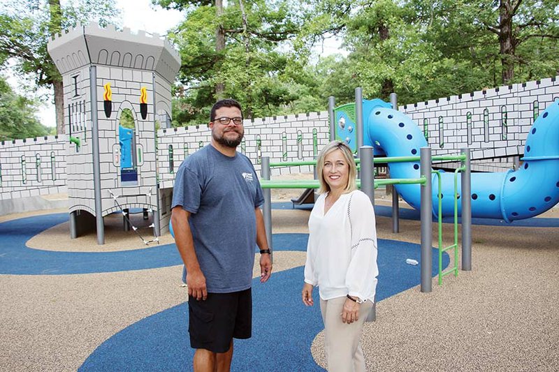 Bryant Parks and Recreation Director Chris Treat, left, and Bryant Mayor Jill Dabbs stand in front of a piece of the new playground equipment at Mills Park in Bryant. The all-inclusive park is expected to officially open later this month.