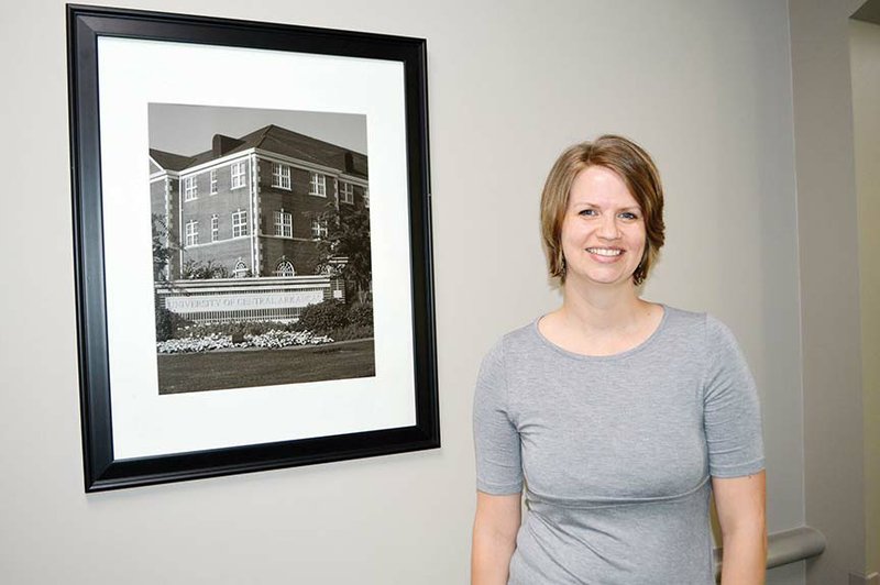 Lesley Graybeal of Conway stands near a photo of the University of Central Arkansas that hangs in the hallway of Brewer-Hegemann Conference Center on campus. Graybeal was named Nonclassified Employee of the Year for the past academic year. She is director of the service-learning program at UCA and has partnerships with more than 100 agencies in central Arkansas to provide volunteer opportunities for students through course-based projects.