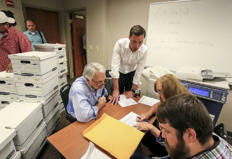 Don Tilton (from left) and Nate Steel turn over petitions calling for legalized casinos to Leslie Bellamy of the state Elections Division and elections attorney Peyton Murphy at the secretary of state’s office Friday. 