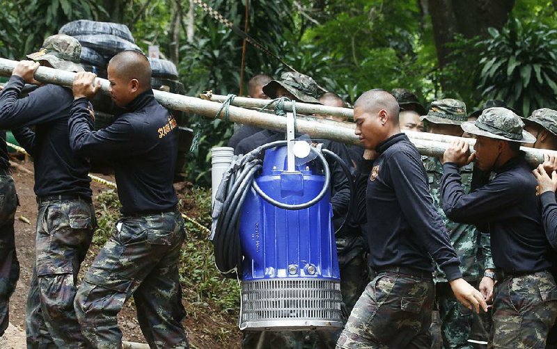 Soldiers carry a pump Friday to help drain water from a northern Thailand cave where 12 boys and their soccer coach have been trapped since June 23. 
