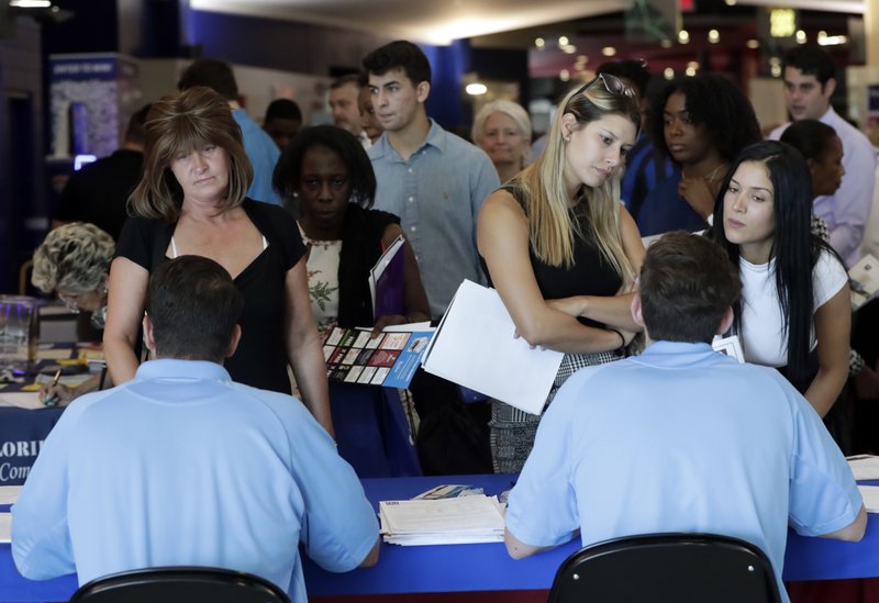 In this Thursday, June 21, 2018 photo, job applicants talks with representatives from Aldi at a job fair hosted by Job News South Florida, in Sunrise, Fla. The Labor Department said Friday, July 6, that the unemployment rate rose to 4.0 percent from 3.8 percent as more people began looking for work and not all of them found it. (AP Photo/Lynne Sladky)
