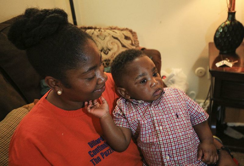 Lakinda Williams holds her 1-year-old son, Aiden, in the living room of their apartment, where black mold has been creeping up the walls and triggering an allergic reaction in Aiden, she said.  
