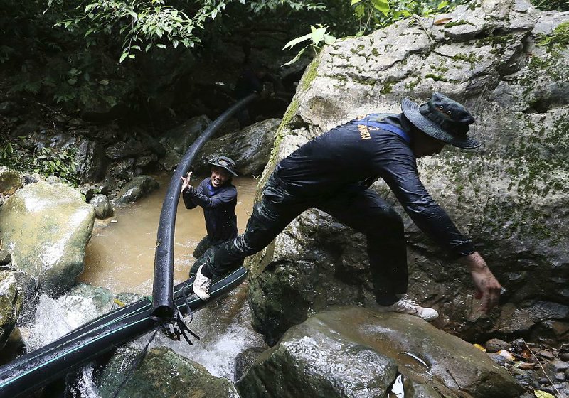 Thai soldiers on Saturday drag a pipe intended to prevent water from entering the cave in Mae Sai where 12 boys and their soccer coach are trapped.  