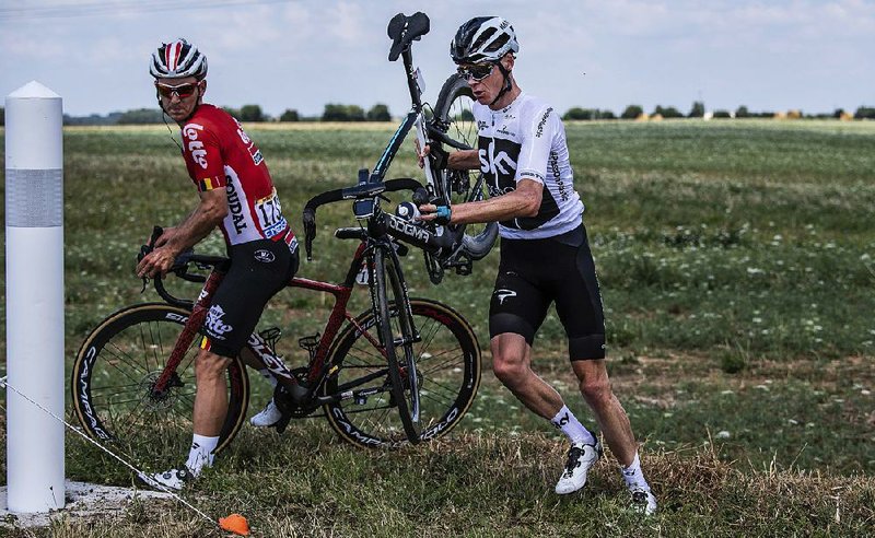 Four-time champion Chris Froome (right) and Jasper De Buyst get back on the road after crashing Saturday in the first stage of the Tour de France. Froome finished the stage in 91st place.