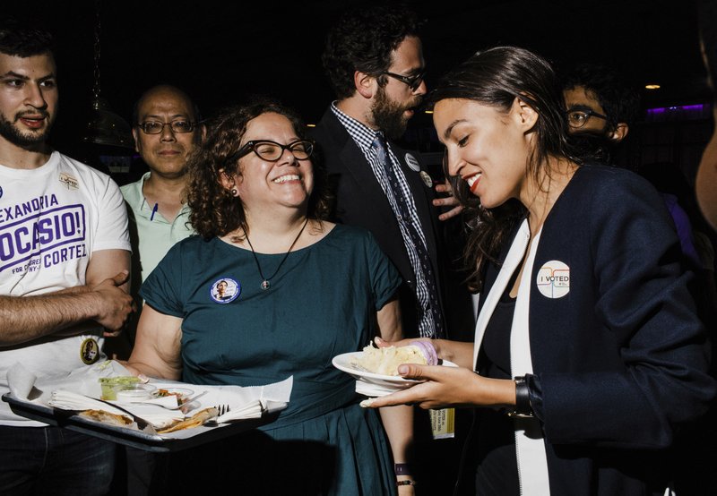 In this June 27, 2018 photo provided by Ocasio2018, Alexandria Ocasio-Cortez, right, 28, celebrates her Democratic congressional primary victory over 10-term incumbent Joe Crowley with campaign manager Virginia Ramos Rios, center left, and campaign staffer Daniel Bonthius, fourth from left, during an election night party at a pool hall in the Bronx borough of New York. Ramos Rios and Bonthius were part of a eclectic team that came together to help their candidate defeat an incumbent who spent $3.4 million on his campaign. (Ocasio2018/Corey Torpie via AP)