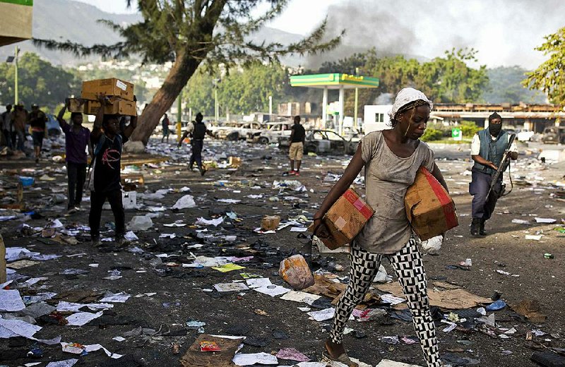 People carry merchandise from the Delimart supermarket complex which was burned during two days of protests against a planned increase in fuel prices in Port-au-Prince, Haiti, on Sunday 
