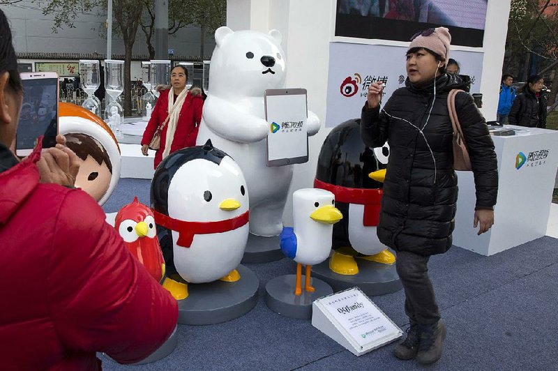 A woman walks past mascots representing the various platforms owned by Chinese Internet conglomerate Tencent during a promotion in Beijing last fall. 