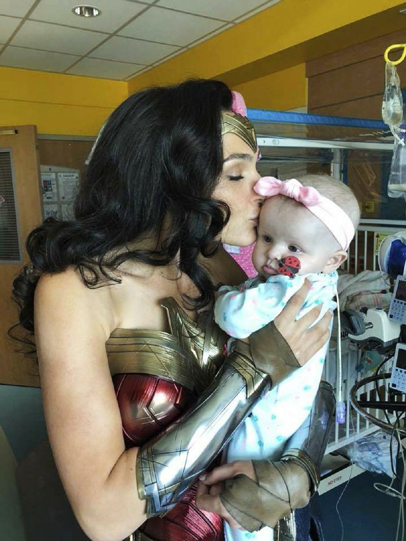 This image released by Kelly Swink Sahady shows Gal Gadot, dressed as Wonder Woman holding Sahady's daughter Karalyne during a visit to Inova Children’s Hospital in Falls Church, Va. Gadot signed autographs and posed for photos with patients and staffers and they posted some of the pictures to social media. (Kelly Swink Sahady via AP)