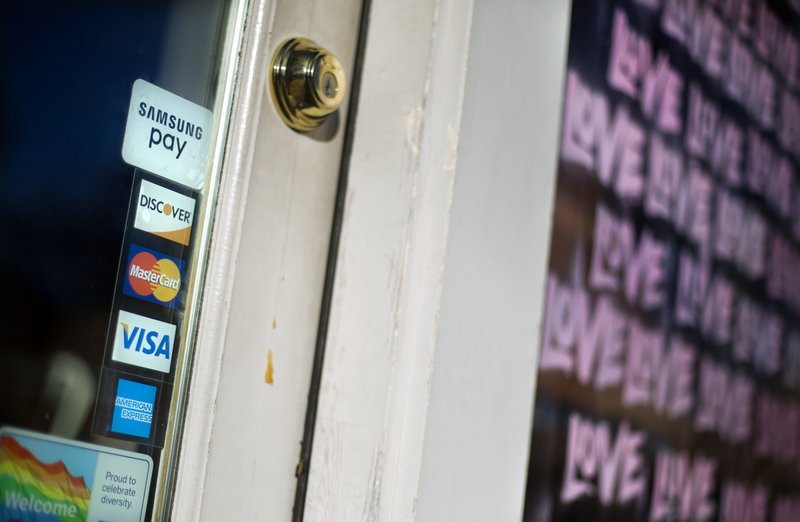 FILE- In this Jan. 31, 2018, file photo, credit card logos are posted to the door of a business in Atlanta.  (AP Photo/David Goldman, File)