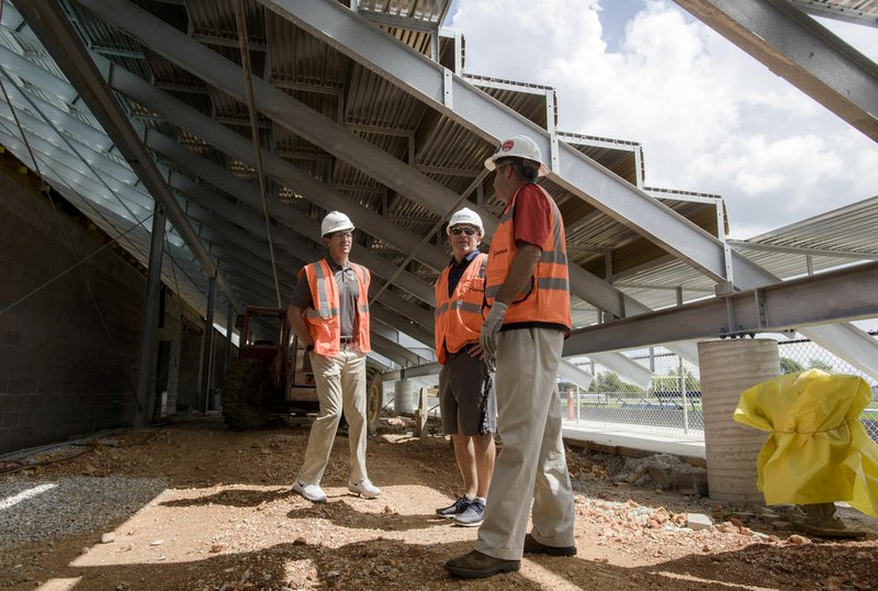 NWA Democrat-Gazette/CHARLIE KAIJO Scott Passmore (from left), district athletic director, West head coach Bryan Pratt and Flintco project manager Scot Hundley stand Monday under the new risers under construction at West High School in Centerton. The West's football stadium is scheduled to host games this fall. Pratt and Hundley gave a media tour to highlight what students and fans can expect.