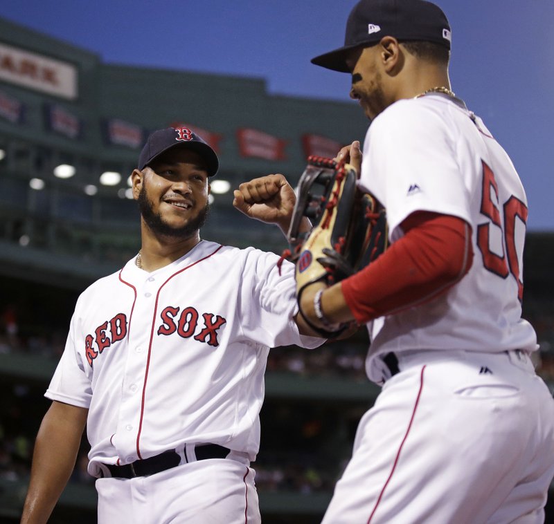Boston Red Sox starting pitcher Eduardo Rodriguez, left, congratulates center fielder Mookie Betts, right, after Betts' leaping catch on a drive by Texas Rangers Elvis Andrus, which ended the top of the fifth inning, during a baseball game against the Boston Red Sox at Fenway Park in Boston, Monday, July 9, 2018. (AP Photo/Charles Krupa)
