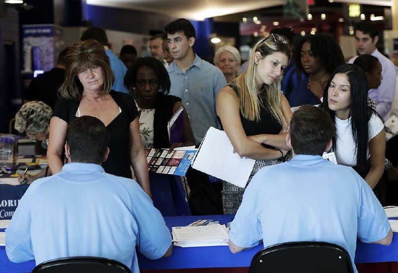 Applicants talk with representatives from the Aldi supermarket chain at a job fair in Sunrise, Fla., last month. 