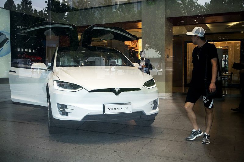 A customer looks at a Tesla Model X electric vehicle on display Saturday at the company’s showroom in Beijing. Tesla has sold cars in China since 2014, but the company ships them from its factory in California.  