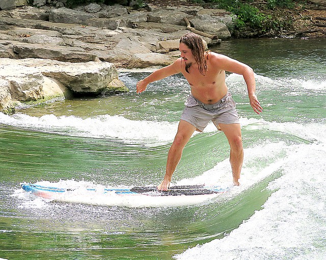 Westside Eagle Observer/RANDY MOLL Jonnie Brown, of Gentry, tests his skill at surfing in the whitewater of Siloam Springs Kayak Park on July 3. He and Dalton Morris, also of Gentry, used paddle boards in the river.