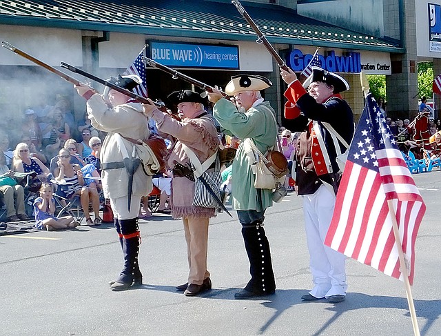 Lynn Atkins/The Weekly Vista Members of a group of Revolutionary War re-enactors fired muskets at the start of the 12th annual Fourth of July Patriots Parade in Sugar Creek Center on July Fourth.