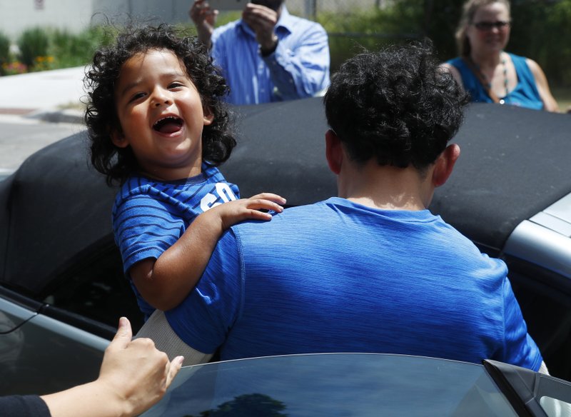 Ever Reyes Mejia, of Honduras, carries his son to a vehicle after being reunited and released by United States Immigration and Customs Enforcement in Grand Rapids, Mich., Tuesday, July 10, 2018. Two boys and a girl who had been in temporary foster care in Grand Rapids were reunited with their Honduran fathers after they were separated at the U.S.-Mexico border about three months ago. (AP Photo/Paul Sancya)