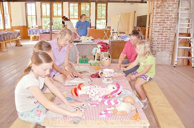 RACHEL DICKERSON/MCDONALD COUNTY PRESS Children learn to sew by hand using doll dress patterns made from newspaper at the New Bethel School near Anderson.