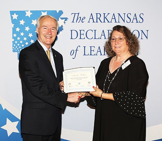 Submitted photo HONORED TEACHER: Pamela Wallace, right, shakes hands with Gov. Asa Hutchinson, who recognized her for her dedication to the Arkansas Declaration of Learning program. Wallace is a sixth-grade social studies teacher at Hot Springs Intermediate School.