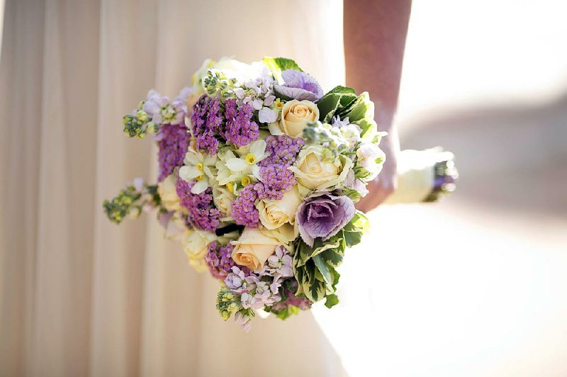 FILE — A bride holds a bouquet during her wedding.
