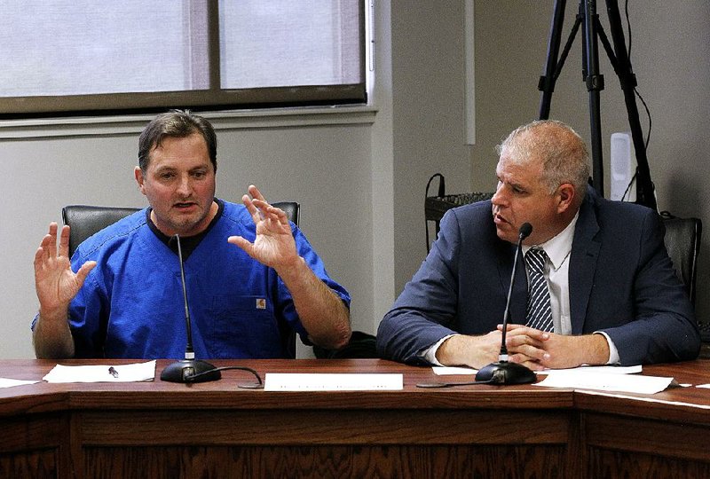 Dr. Carlos Roman (left), seated with fellow marijuana board member James Miller, said Thursday that hiring a consultant seemed “the quickest way” to assess firms seeking to dispense cannabis in the state.  