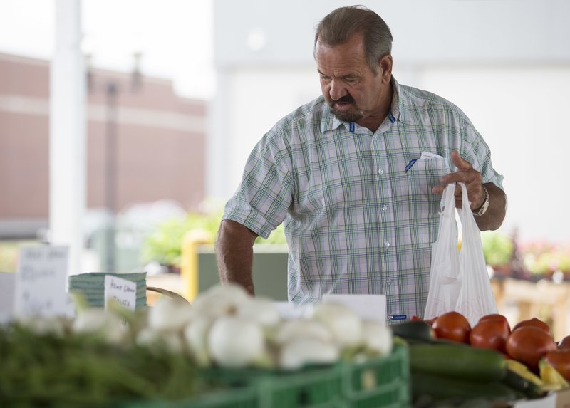 In this June 13, 2018, file photo, Bob Harris carefully selects which tomatoes to buy at Paducah, Kentucky's Downtown Farmers' Market.  (Ellen O'Nan/The Paducah Sun via AP, File)