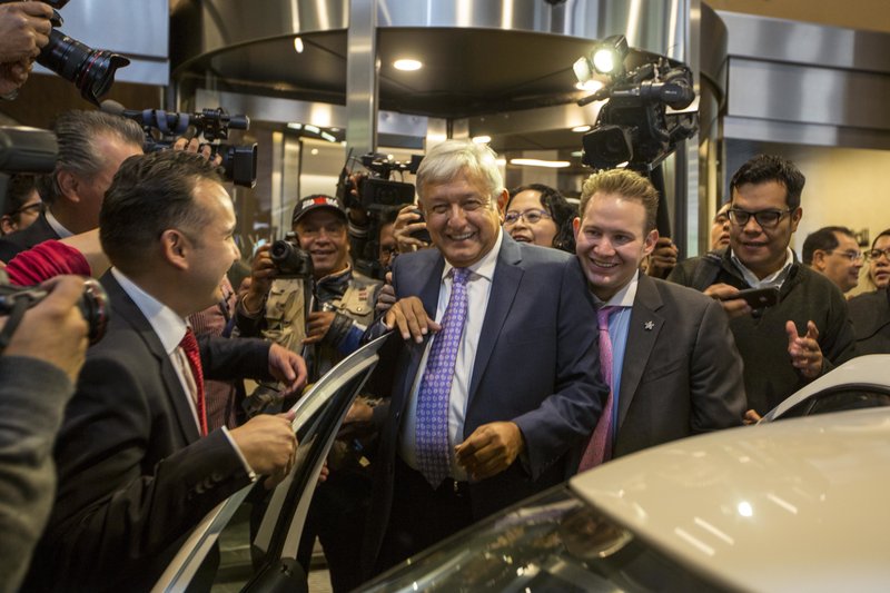 Mexico's President-elect Andres Manuel Lopez Obrador is surrounded by the press as he leaves a hotel where he gave a press conference in Mexico City, Monday, July 9, 2018.  (AP Photo/Moises Castillo)