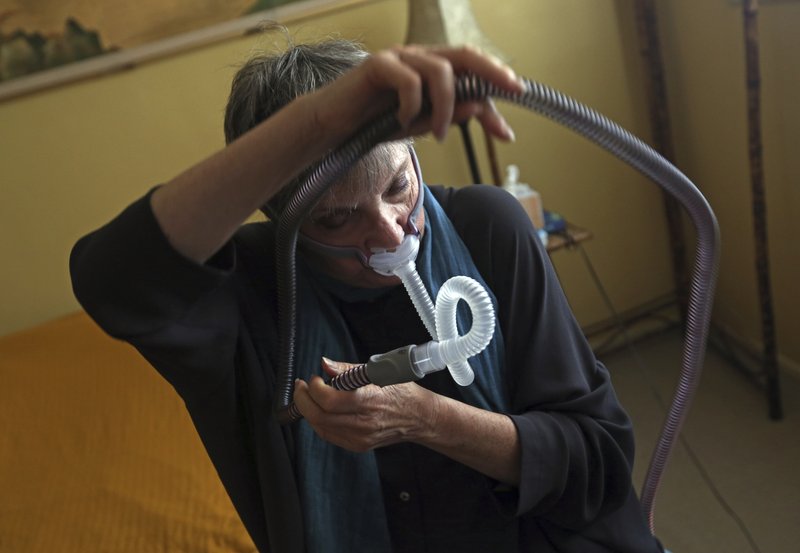 Joelle Dobrow demonstrates how she puts on her sleep apnea breathing device at her home in Los Angeles Thursday, July 12, 2018. It's been two decades since doctors fully recognized that breathing that stops and starts during sleep is tied to a host of health issues, even early death, but there still isn't a treatment that most people find easy to use. Dobrow said it took her seven years to find one she liked. "I went through 26 different mask styles," she said. "I kept a spreadsheet so I wouldn't duplicate it." (AP Photo/Reed Saxon)