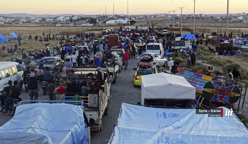 This June 30, 2018 file photo provided by Nabaa Media, a Syrian opposition media outlet, shows people in their vehicles who fled from Daraa, gathering near the Syria-Jordan border. Syrian activists and state media said Thursday, July 12, 2018 that the rebels have agreed to surrender Daraa, the first city to revolt against President Bashar Assad with Arab Spring-inspired protests seven years ago, to government forces. (Nabaa Media, via AP, File)