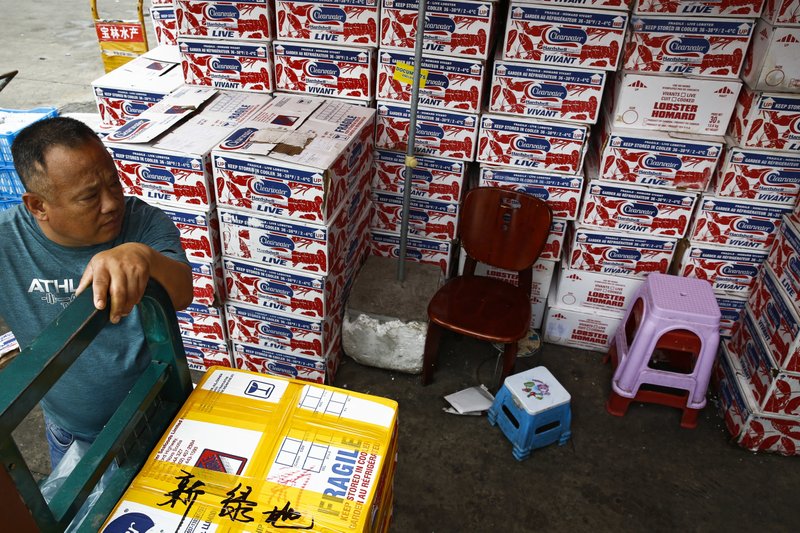 A man waits for the goods to be load on his tricycle at a dealer selling imported seafoods at the Jingshen seafood market in Beijing, Thursday, July 12, 2018. China's government vowed on Wednesday to take "firm and forceful measures" as the U.S. threatened to expand tariffs to thousands of Chinese imports like fish sticks, apples and French doors, the latest salvo in an escalating trade dispute that threatens to chill global economic growth. (AP Photo/Andy Wong)