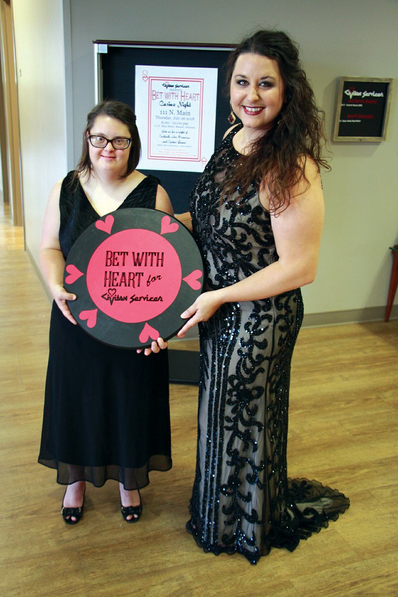 Lyndsey Smith, left, and Bekka Wilkerson, special events coordinator for Civitan Services, pose with a giant poker chip inside the offices for the adult-service campus in Bryant. Civitan Services will host the first Bet With Heart Casino Night on July 26