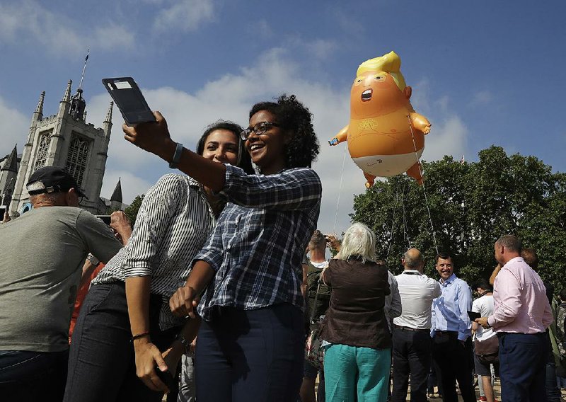 People in London’s Parliament Square take photos of a balloon depicting President Donald Trump as an angry baby that was flown as a protest against his trip to England.  