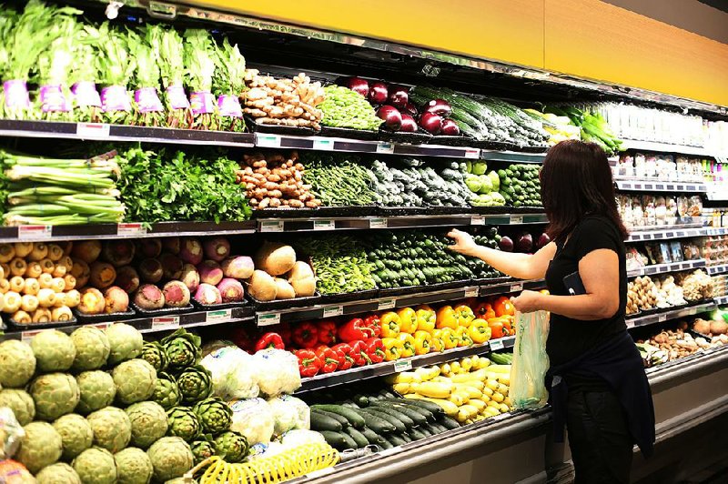 A customer selects cucumbers during the grand opening of a Whole Foods Market in Burbank, Calif., in June.  