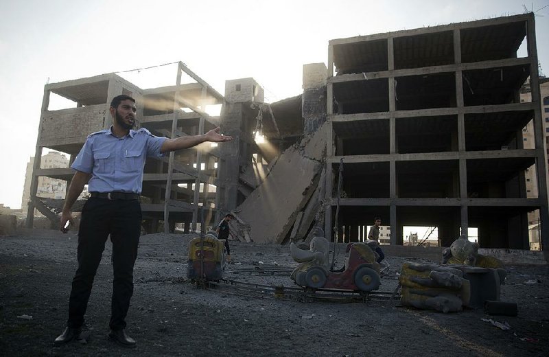 A Palestinian policeman stands guard next to a building destroyed Saturday by an Israeli airstrike in Gaza City. 