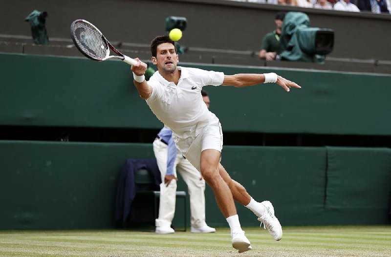 Novak Djokovic returns a ball to Rafael Nadal during Saturday’s Wimbledon men’s singles semifinal match in London. Djokovic won 6-4, 3-6, 7-6 (9), 3-6, 10-8 to advance to today’s final against Kevin Anderson.  