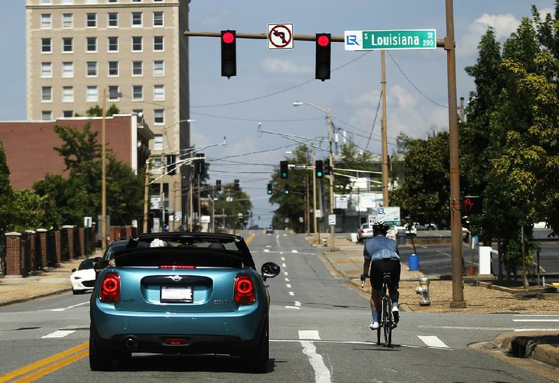 A cyclist and a car share the road Saturday at Louisiana and Third Streets in Little Rock. The city is embarking on the Friendly Driver Program to educate drivers and bicyclists on how to better share the streets. 