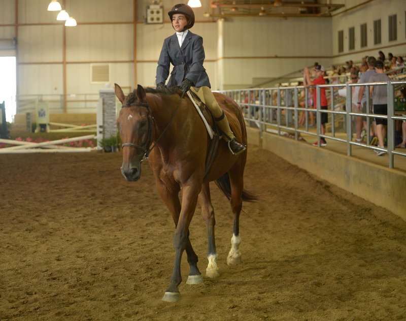 NWA Democrat-Gazette/ANDY SHUPE Abery Gabriele, 11, of Bella Vista rides atop Ollivander The Bay on Saturday as they compete in the Cross Rail Challenge during the 11th annual Northwest Arkansas Hunter Jumper Association Summer Classic at the Pauline Whitaker Animal Science Arena in Fayetteville.