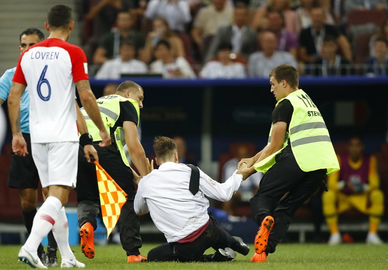 Security stewards remove people who ran onto the pitch and briefly stopped the final match between France and Croatia at the 2018 soccer World Cup in the Luzhniki Stadium in Moscow, Russia, Sunday, July 15, 2018. 