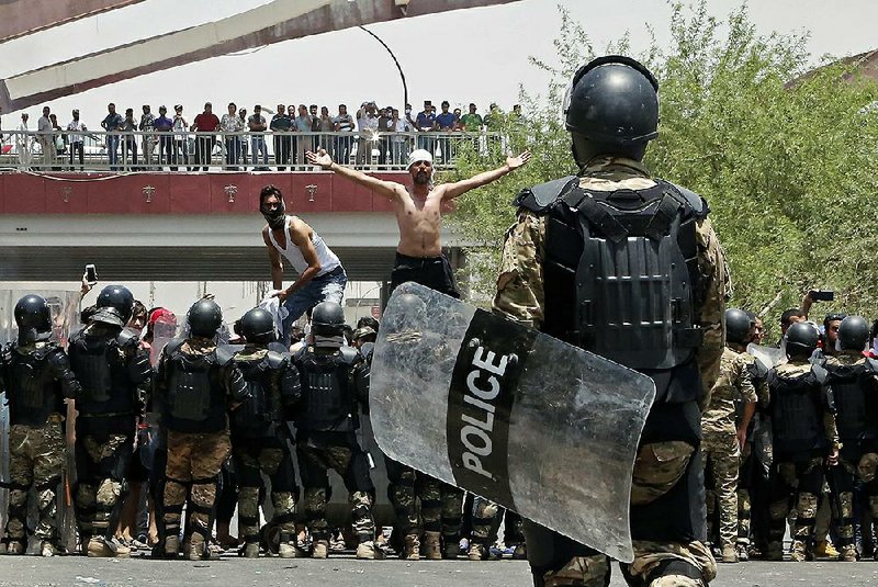 Iraqi riot police prevent protesters from storming the provincial council building during a demonstration Sunday in Basra.  
