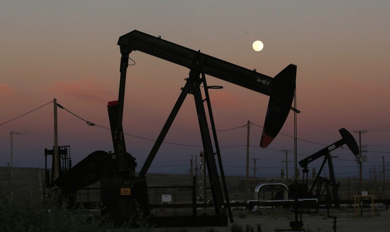 FILE - In this June 8, 2017, file photo, oil derricks are busy pumping as the moon rises near the La Paloma Generating Station in McKittrick, Calif. The U.S. is on pace to leapfrog both Saudi Arabia and Russia as the world's biggest oil producer. (AP Photo/Gary Kazanjian, File)
