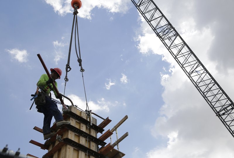 In this June 2018 photo, a member of a construction team works on the site of Gables Station, a mixed use project featuring apartments, retail, a hotel and cafes, in Coral Gables, Fla. Most U.S. business economists expect corporate sales to grow over the next three months and hiring and pay to rise with them. Goods producers — a category that includes manufacturers, farmers and construction — are most optimistic, with 94 percent saying they expect sales to rise over the next three months. (AP Photo/Lynne Sladky, File)
