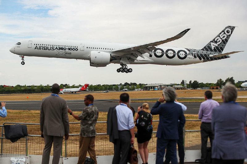 Spectators watch an Airbus SE A350-1000 aircraft land Monday on the opening day of the Farnborough International Airshow in Farnborough, England. The biannual showcase for the aviation industry runs through Sunday.  
