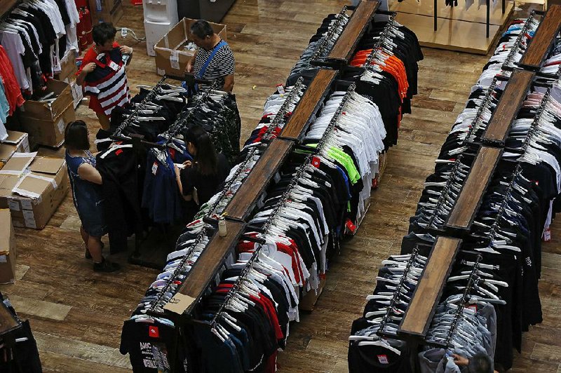 People shop for garments at a retail and wholesale clothing mall in Beijing on Monday. The pace of China’s economic growth slowed in the quarter ending in June, adding to challenges for Beijing amid a mounting trade dispute with Washington.  